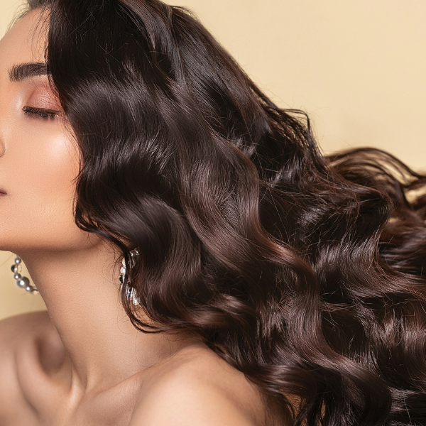 A brunette with long wavy hair and hoop earrings has her eyes closed