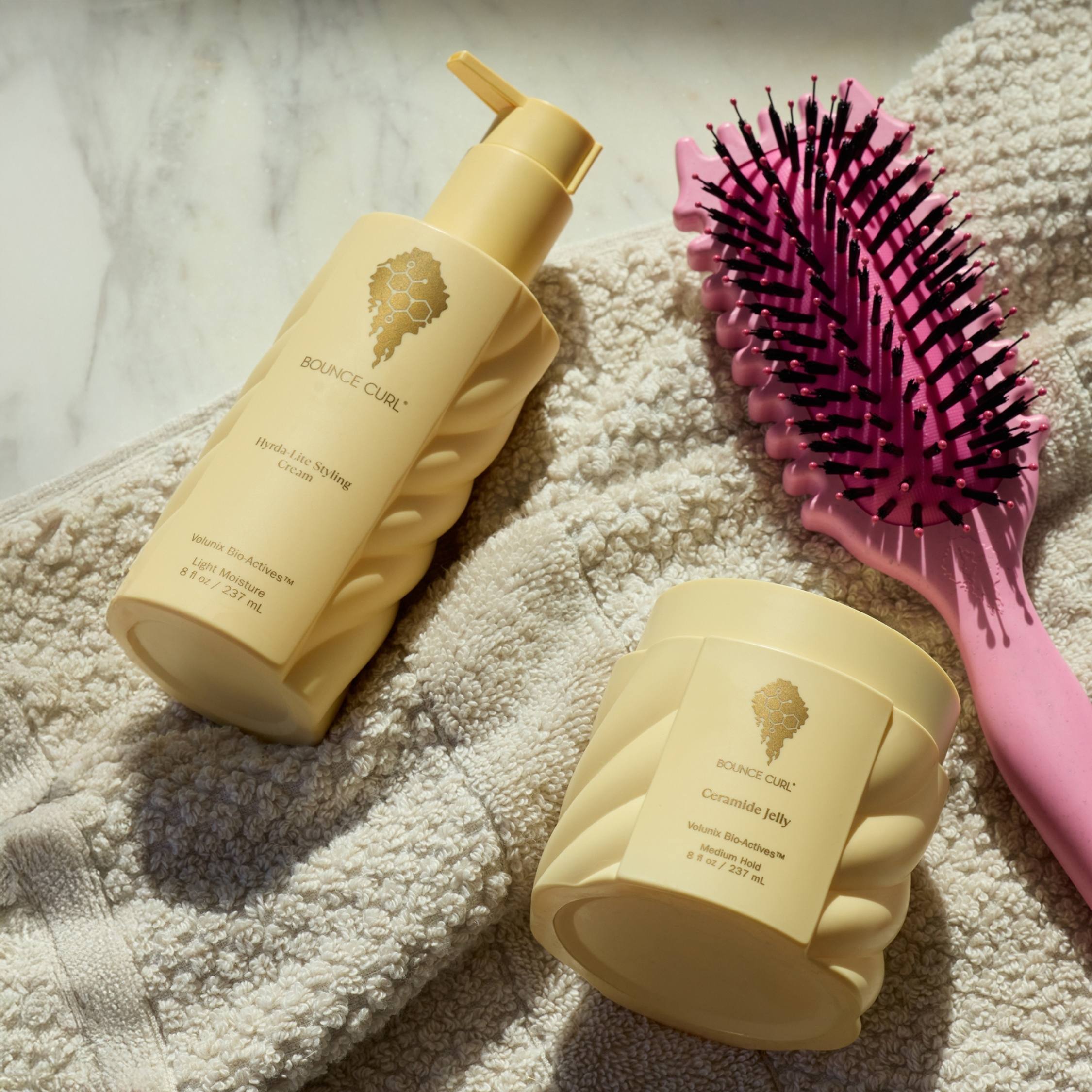 Yellow hair care products and pink brush on a textured surface