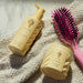Yellow hair care products and pink brush on a textured surface