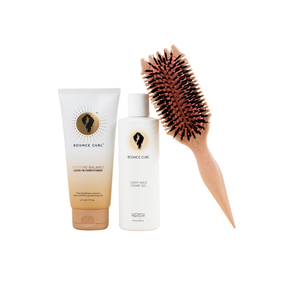 Hair care products including a tube and bottle with a brush on a white background