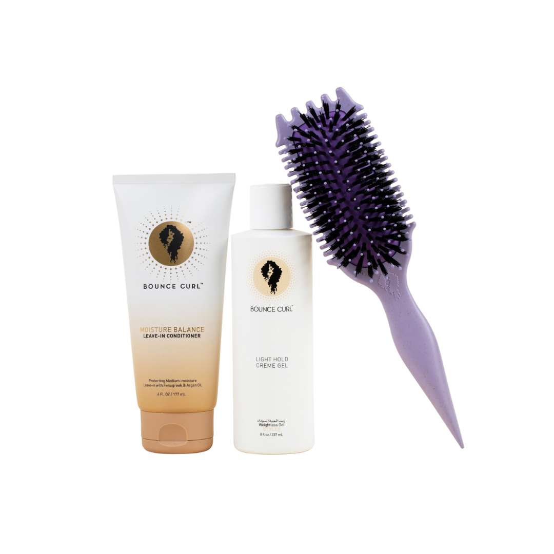 Hair care products including a tube and bottle with a brush on a white background