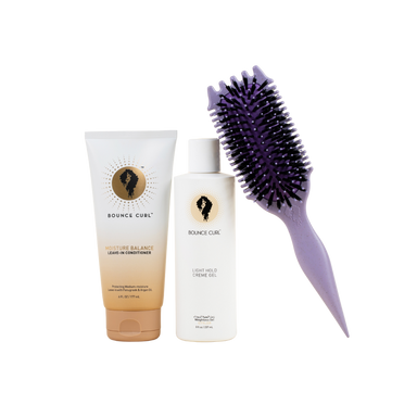 Hair care products including a tube and bottle with a brush on a white background