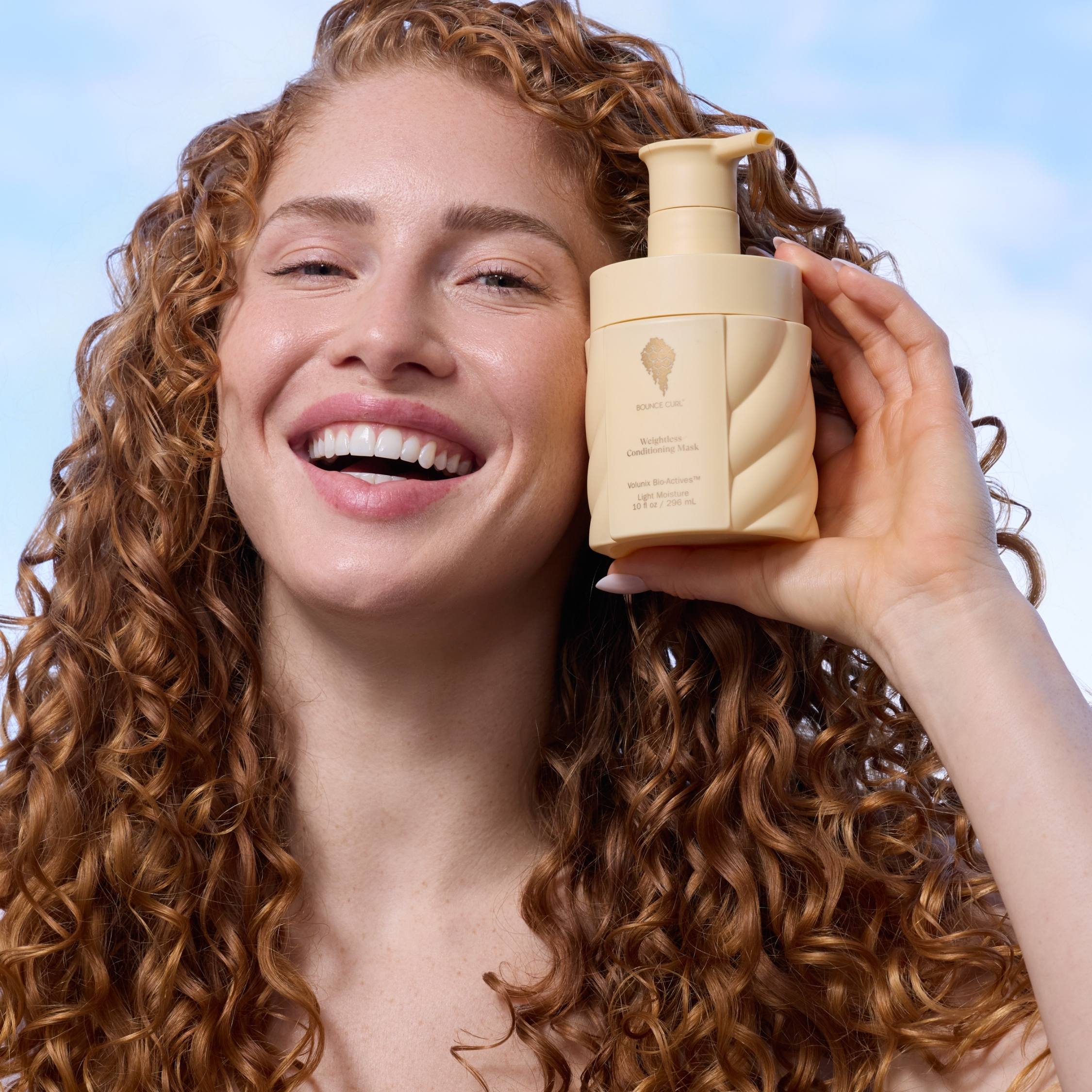 Woman holding a beige bottle with a textured surface against a light blue background