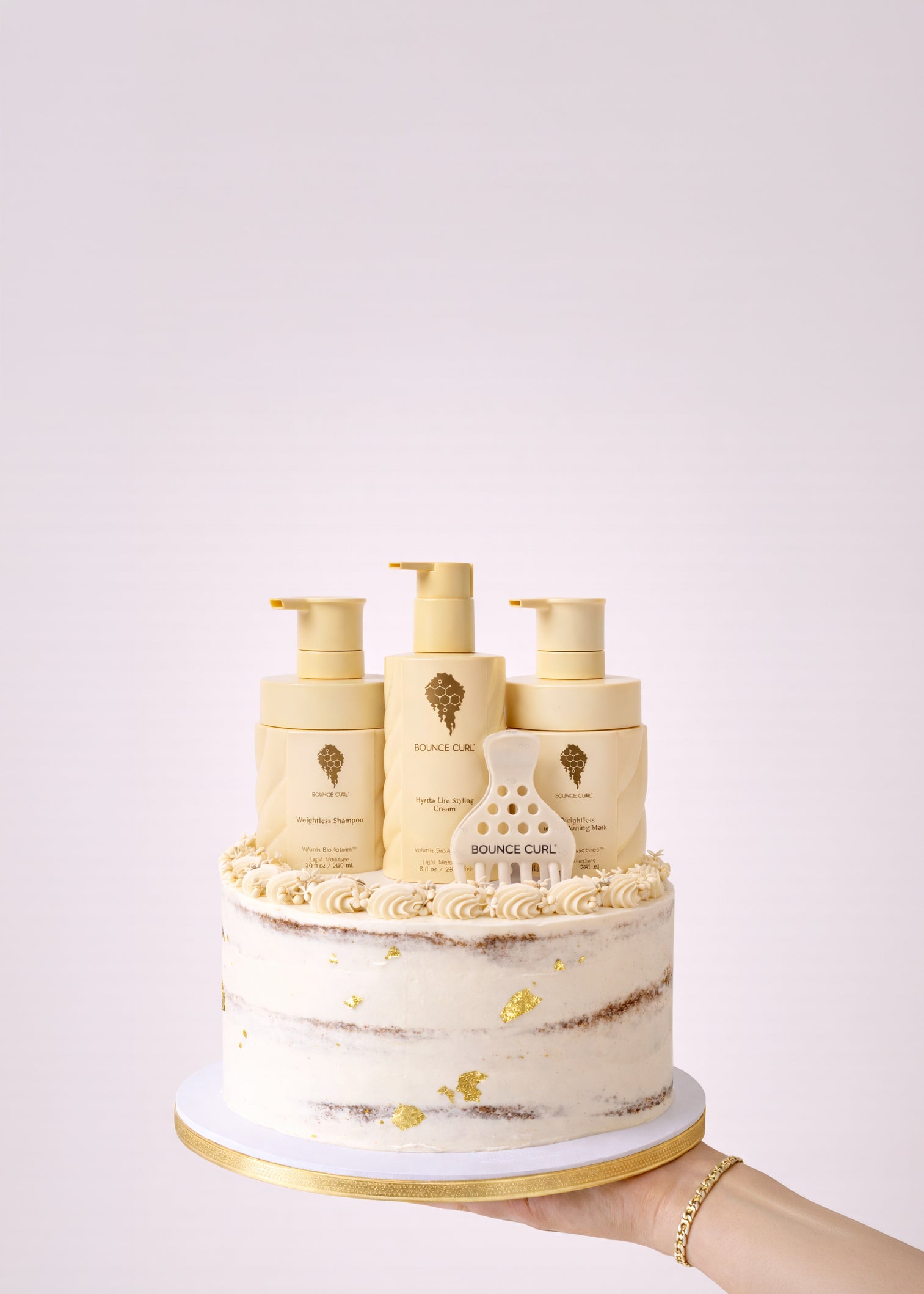 Cake-shaped display of Bounce Curl hair care products on a white background