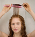 Woman with wet hair holding a pink brush through her curls
