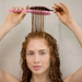Woman with wet hair holding a pink brush through her curls