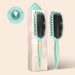 Teal hairbrush with black bristles next to its packaging on a beige background